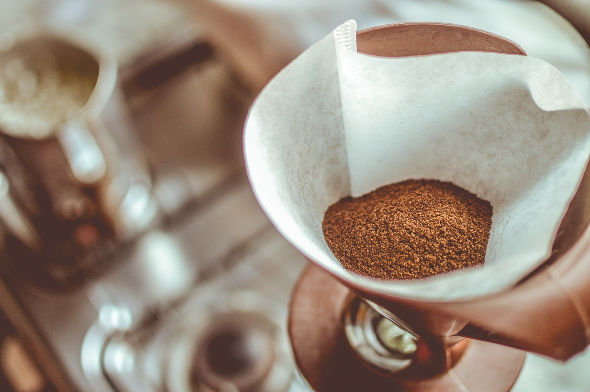 Een filter voor filterkoffie gevuld met gemalen koffie boven een koffiezetter
